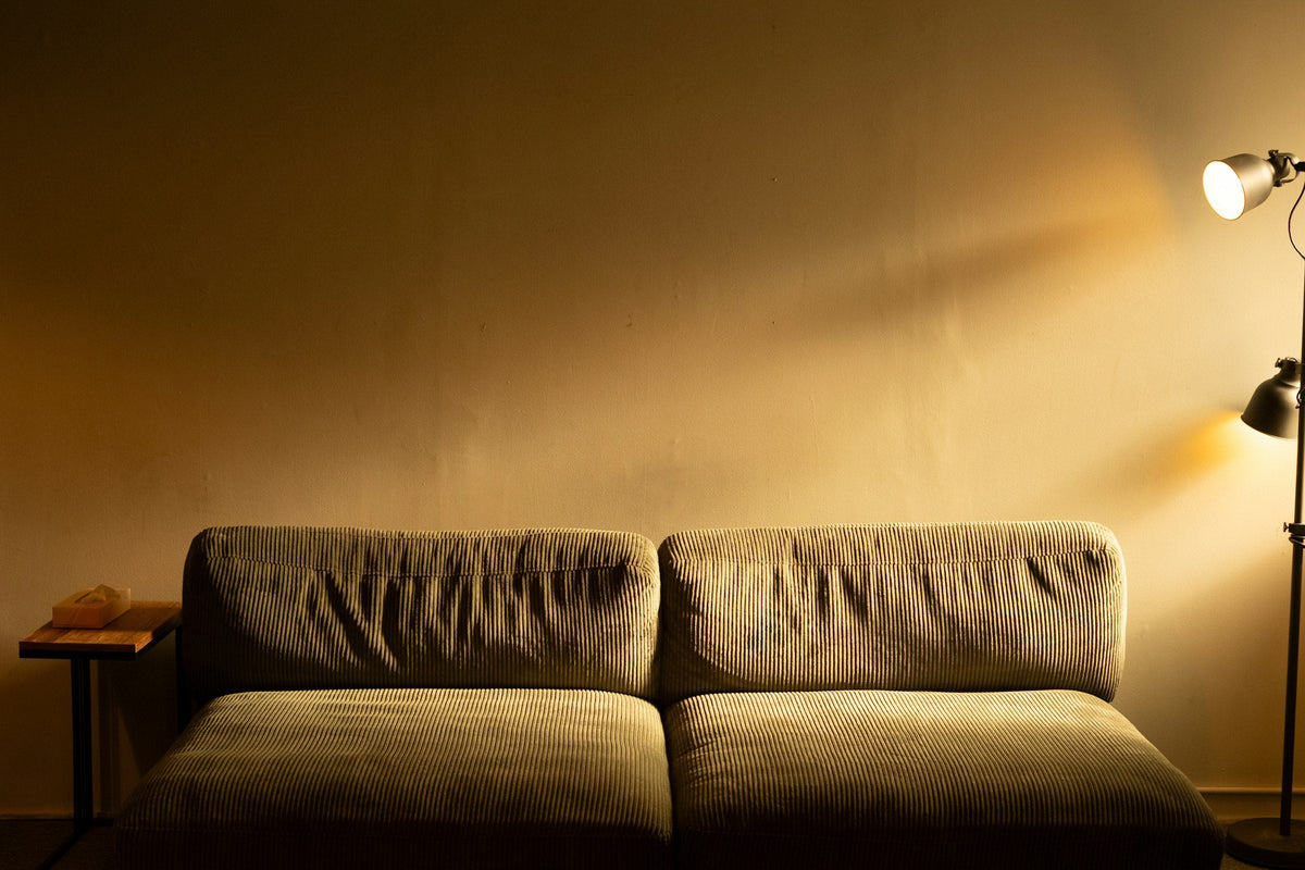 Warm floor lamp beside a sofa in a softly lit interior