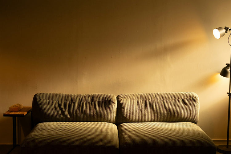 Warm floor lamp beside a sofa in a softly lit interior